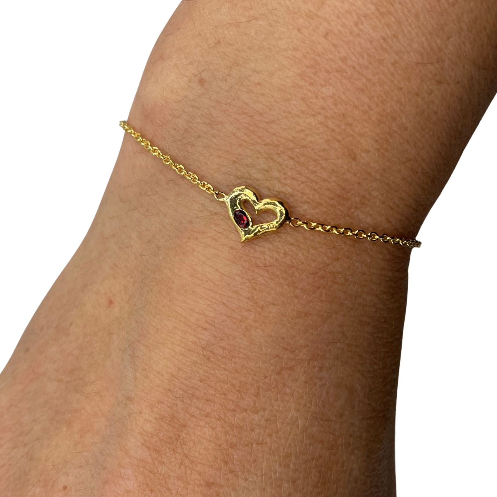 Gold heart with red garnet bracelet by Amy Delson on wrist
