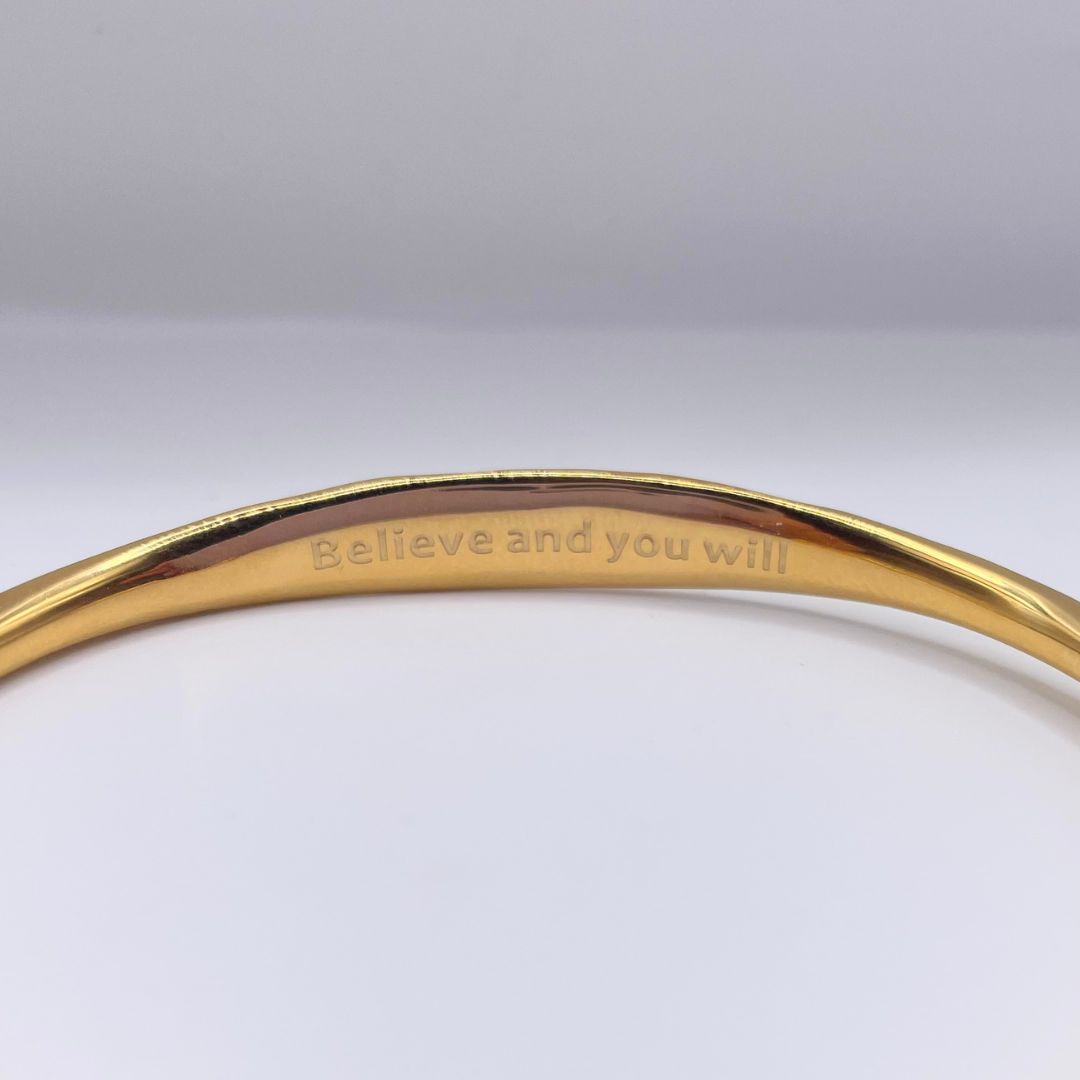 Inner engraving: Believe and you will on gold cuff by Amy Delson