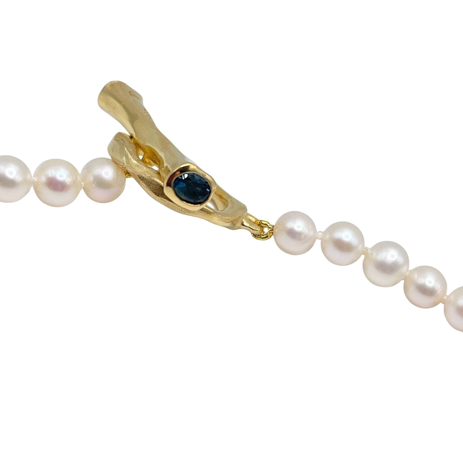 Pearl necklace with a gold clasp featuring a blue gemstone by
Amy Delson
