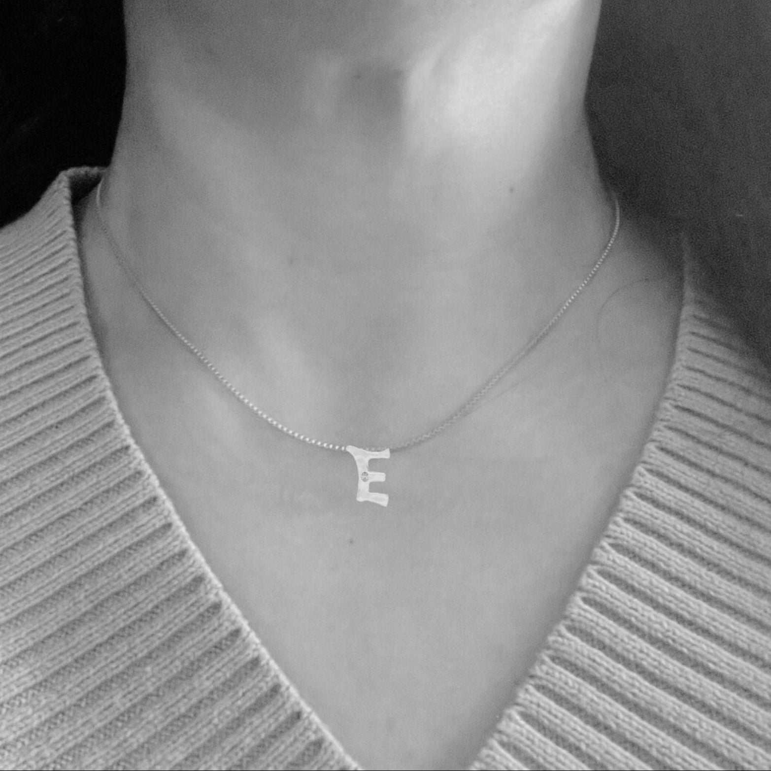 Model wears white gold with lab diamond letter E necklace by Amy Delson
