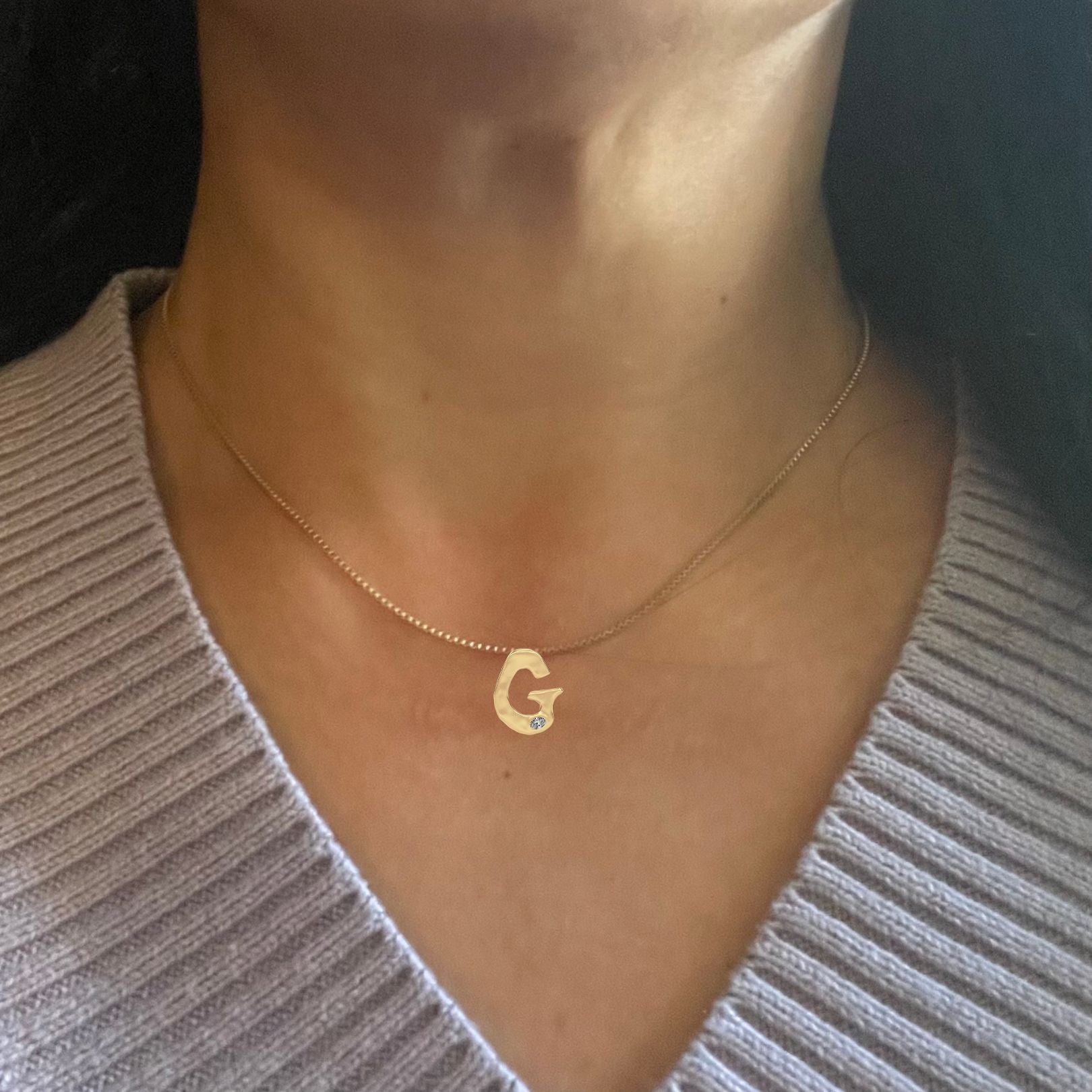 Gold diamond G necklace shown on a woman's neck