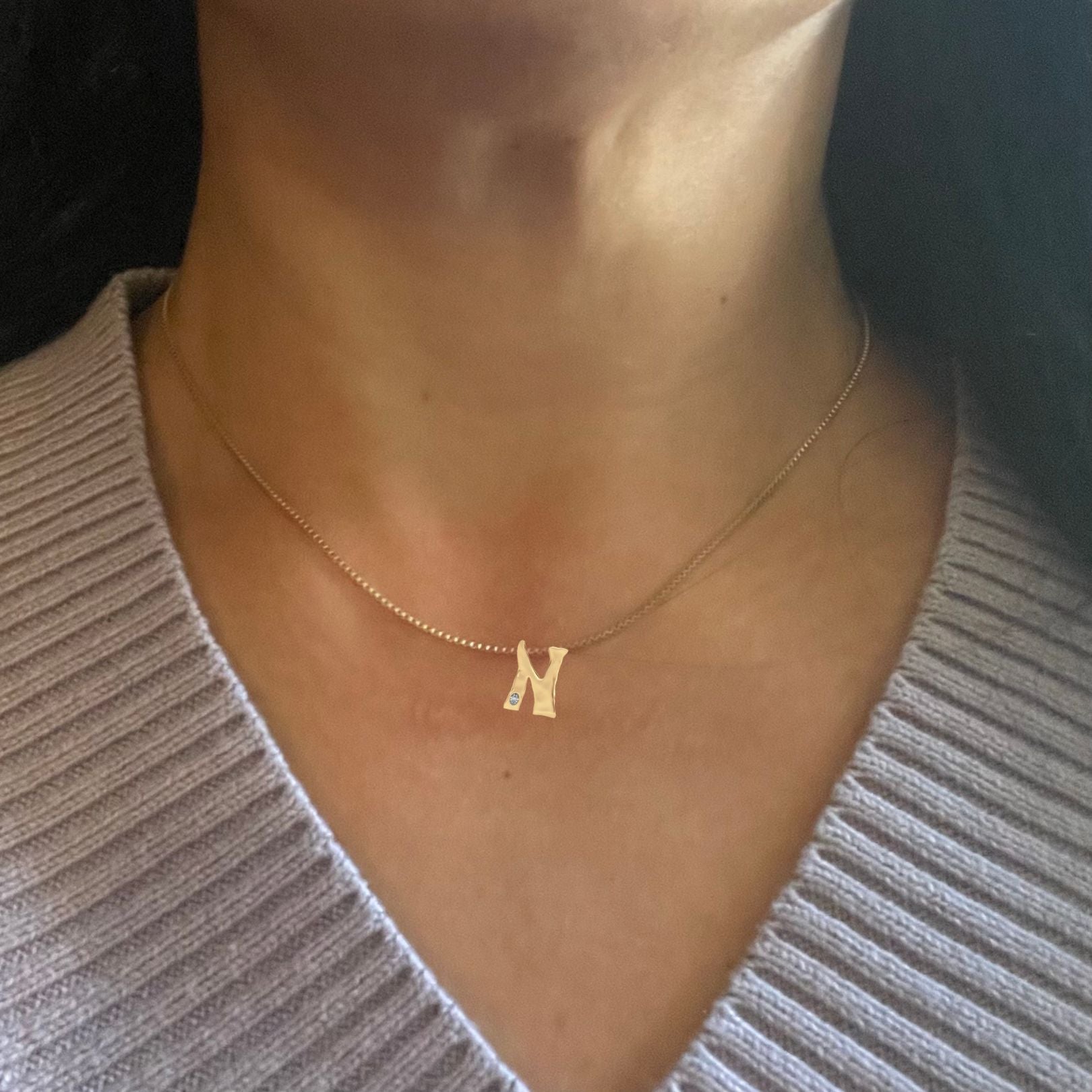 Gold diamond letter N necklace shown on woman's neck