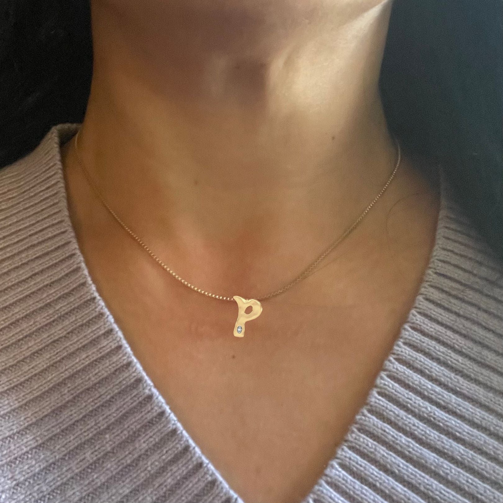 Gold diamond letter P necklace shown on woman's neck