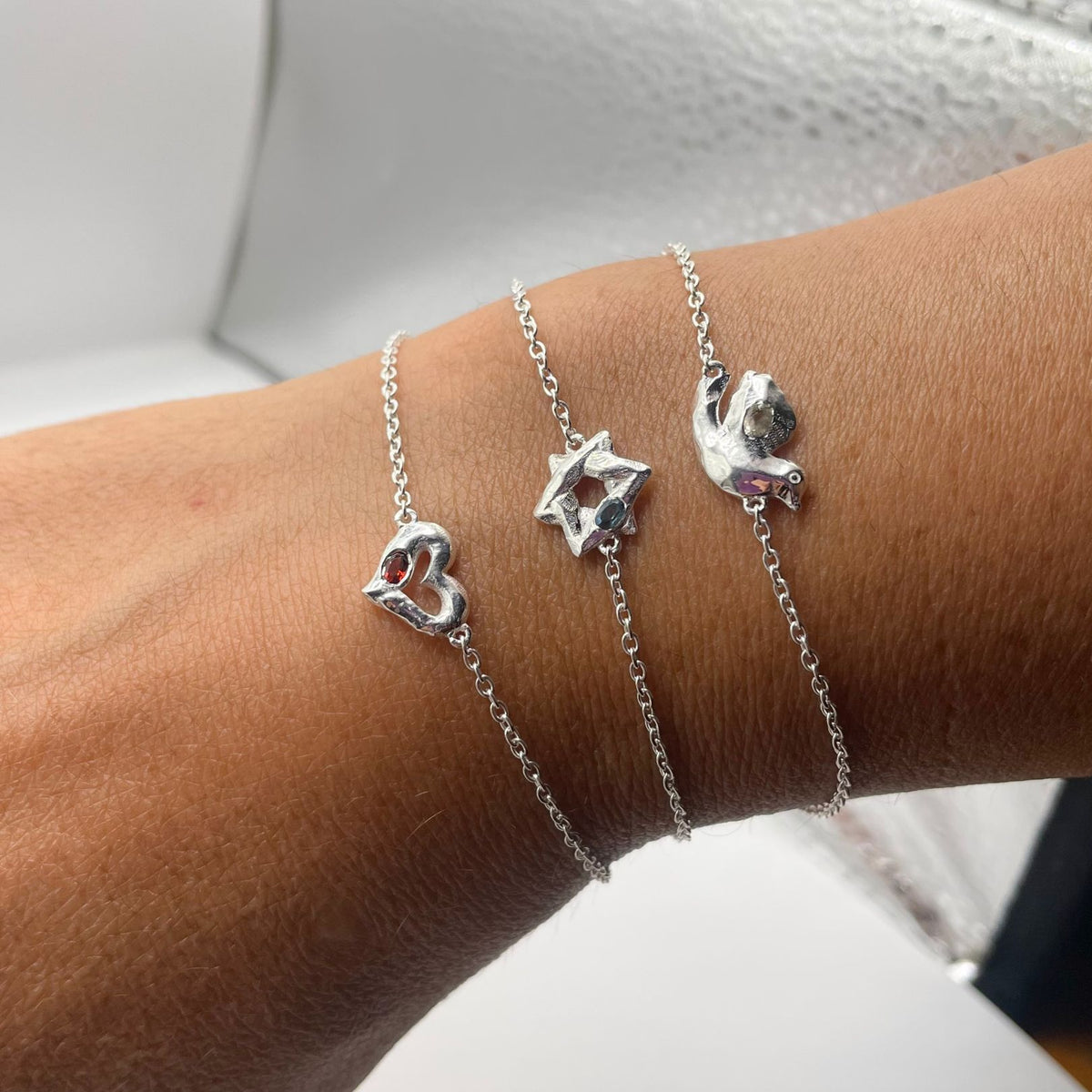 Silver dove heart star bracelets by Amy Delson worn on wrist