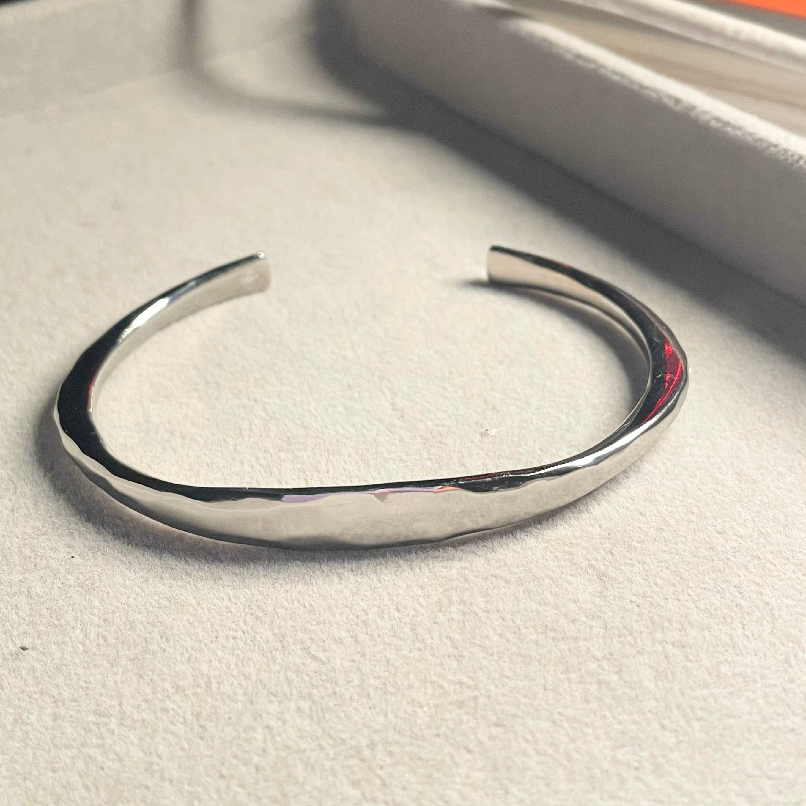 Silver forged cuff by Amy Delson on grey background