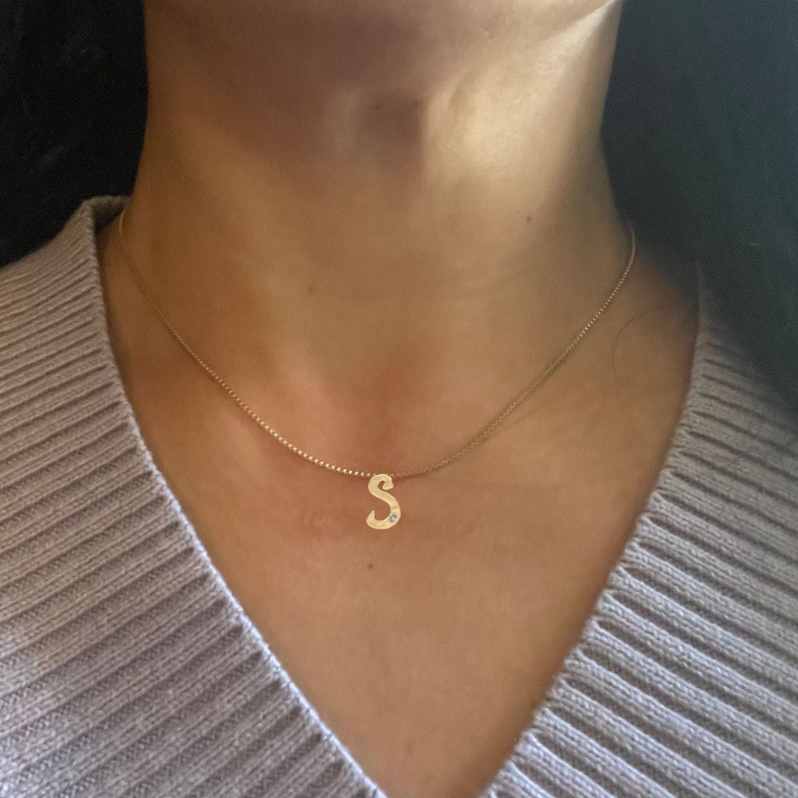 Gold diamond letter S necklace shown on woman's neck
