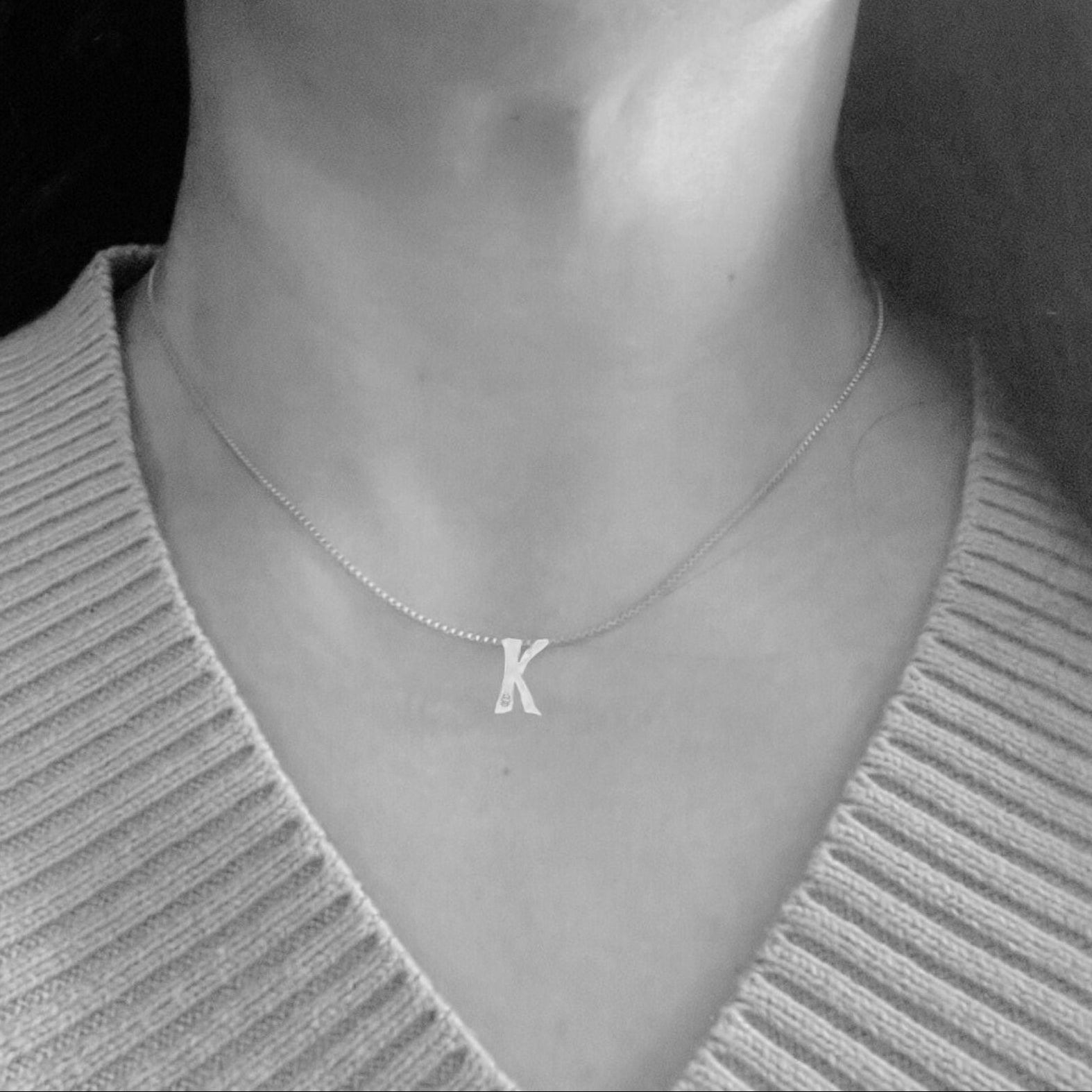 Model wears Letter K white gold necklace with lab diamond by Amy Delson
