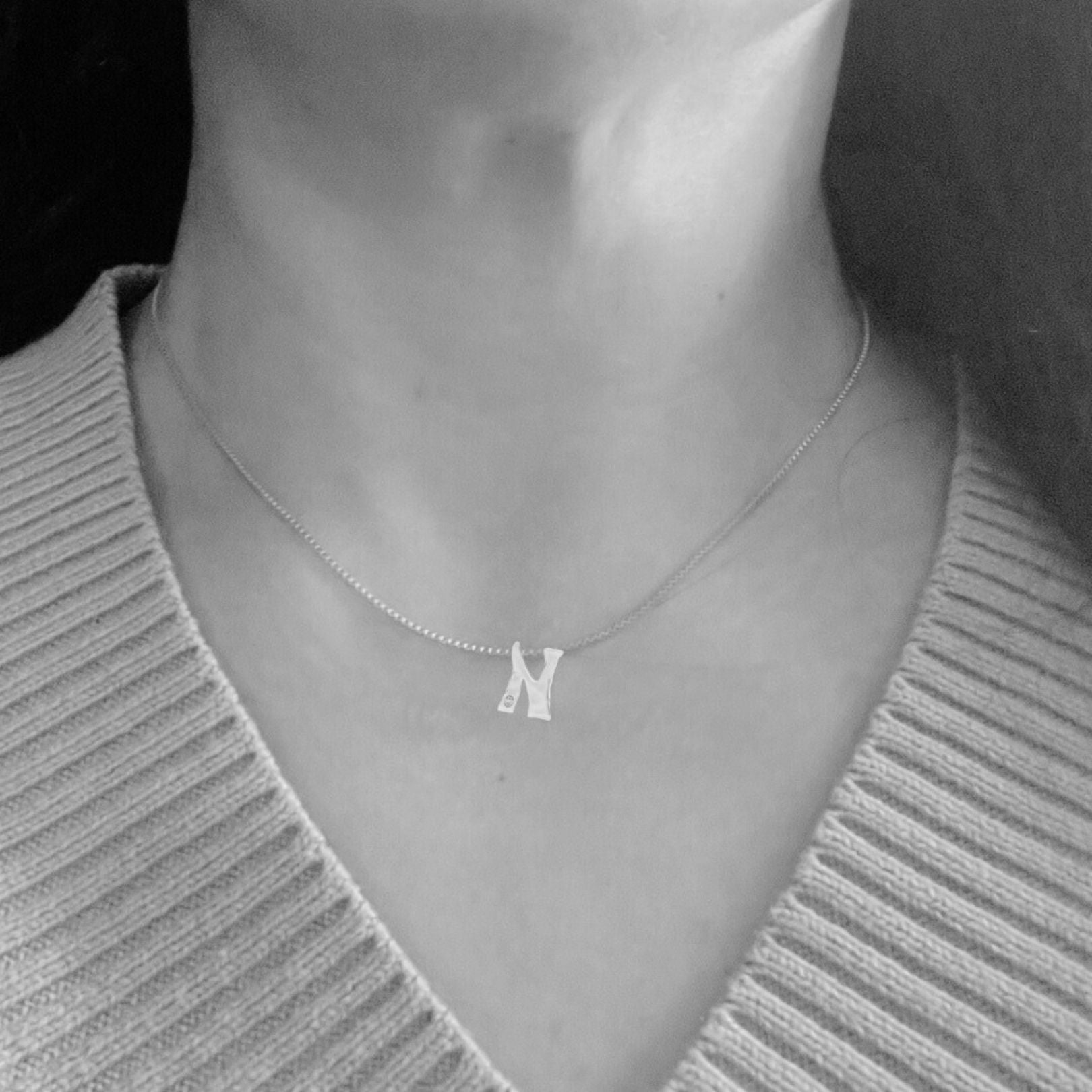 Model wears white gold with lab diamond letter N necklace by Amy Delson